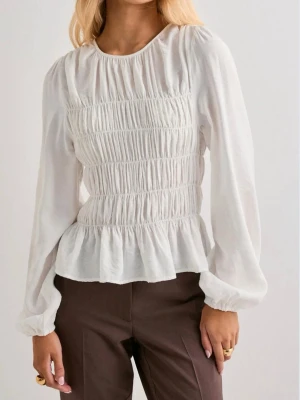 Vit blus med smock  - Säljer en vit blus med smockad front och volang nedtill. Blusen har rund halsringning och långa ärmar med resår vid ärmslut. Materialet ser ut att vara lätt och luftigt, perfekt för en trendig look. Ny pris 300. Säljer då den är lite för stor för mig. Använd fåtals gånger. Pris kan diskuteras 