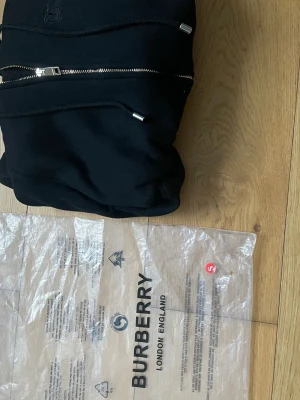 Svart hoodie från Burberry med dragkedja - Jag säljer en Burberry kofta i storlek xs påsen är det ett litet hål i tyvär 