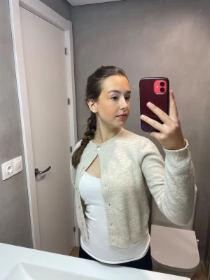 Beige cardigan från H&M - Säljer en enkel och stilren beige kofta från H&M. Koftan har rund halsringning, långa ärmar och knappar framtill. Tröjan är väll använd.