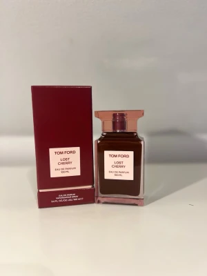 Tom Ford Lost Cherry EdP 100 ml - Tom Ford Lost Cherry Eau de Parfum i 100 ml flaska. Parfymen kommer i en elegant, fyrkantig glasflaska med rödbrun färg och matchande röd kartong. Flaskan har en stilren etikett och ett exklusivt utseende som verkligen sticker ut på parfymhyllan.