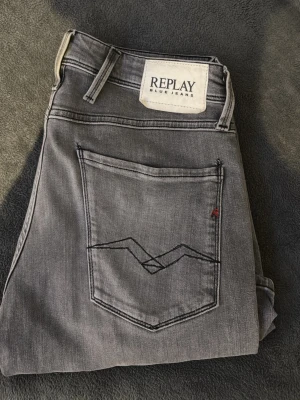 Grå jeans från Replay Blue Jeans - Snygga grå jeans från Replay Blue Jeans med klassisk femficksmodell och coola svarta sömmar på bakfickan. Jeansen har normal midja och raka ben. Tillverkade i bomull med en liten del elastan för extra komfort. Perfekta för en avslappnad och trendig look. Modellen är slim fit Mitt pris 500kr🤝 