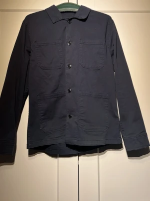 Navy overshirt från Lindbergh - Stilren navy overshirt i  bra skick. Perfekt lager-på-lager-plagg för en avslappnad look. Overshirten är i storlek S men sitter mer som M. Priset är ej hugget i sten Bara att skicka vid funderingar!! 