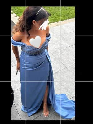 Lång blå balklänning med slits - Elegant lång blå klänning med offshoulder och v-ringad urringning. Klänningen har glittriga detaljer upptill och en hög slits framtill. Perfekt för bal eller festliga tillfällen. Använd under 2 tillfällen, finns inga skador, och klänningen är som ny 😍 