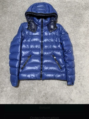Blå dunjacka från Moncler med huva - Hej, säljer nu denna otroligt snygga Moncler jackan i modellen Bady hooded short down jacket i storlek 3 men passar en m perfekt, mycket fint skick se bilder nyss kemtvättad         Köpte genom Tradera men missa att det va en dam jacka så därför jag säljer äkthets garanterad genom Tradera, har du några funderingar skriv 