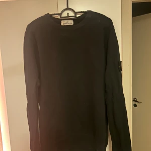 Svart Stone Island sweatshirt M - Svart långärmad sweatshirt från Stone Island i klassisk modell med rund hals och ikonisk patch på ärmen. Tillverkad i mjuk bomull för skön känsla och stilren look. Perfekt för dig som gillar streetwear och vill ha något enkelt men ändå exklusivt.
