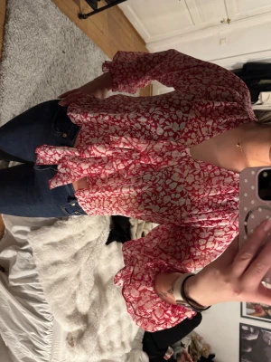Blommig röd och vit blus med knyt - Säljer en luftig blus med röd och vit blommönster, v-ringning och dekorativ knytning framtill. Från Zara❤️
