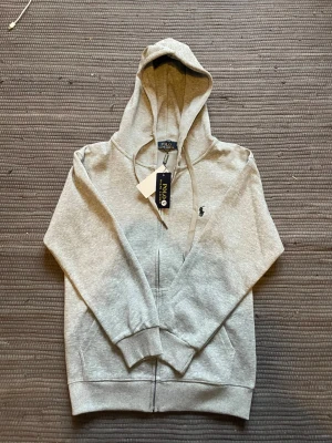 Grå zip hoodie från Polo Ralph Lauren - Snygg grå hoodie från Polo Ralph Lauren med dragkedja icke använd pga den passa inte mig