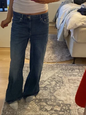 Blåa baggy jeans med låg midja - Säljer ett par klassiska blåa baggy jeans med låg midja och femficksmodell. Jeansen har en avslappnad passform över låren och blir vidare nedtill. Tillverkade i denim med snygg tvätt och knappgylf. Perfekta för en trendig och bekväm stil.