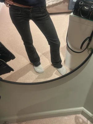 Svarta bootcut jeans med låg midja - Säljer ett par svarta bootcut jeans med låg midja och klassiska fem fickor. Jeansen har en snygg tvätt och sitter tajt över låren för att sedan bli vidare nedtill. Perfekta för dig som gillar en retro vibe och vill ha ett par jeans som sticker ut.