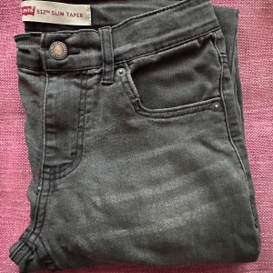 Levi's 512 Slim Taper svarta jeans - Snygga svarta Levi's 512 Slim Taper jeans med smal passform och avsmalnande ben. Klassisk femficksmodell med silverfärgade nitar och knapp, samt Levi's ikoniska röda etikett på bakfickan. Tillverkade i mjuk denim med stretch för extra komfort. Jeansen är nästan oanvända och extremt bekväma! Priset är såklart inte hugget i sten och går att diskutera vid snabba affärer.