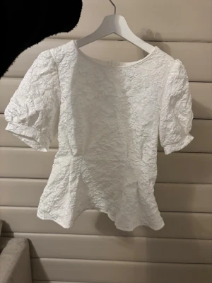 Vit topp - Säljer en vit blus med puffärmar och strukturerat tyg använd 1 gång