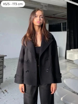 Svart kappa - Säljer min svarta kappa då jag inte får någon användning för den längre… Har storlek xs/s precis som modellen på bilden! Har knappt använt jackan men den tar lätt åt sig av hår och ludd från halsduken. Kappan är från design by si. Nypris 757kr