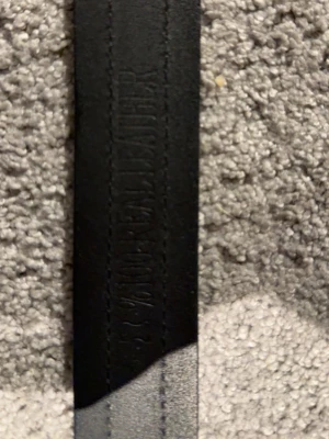 Svart Gucci bälte med GG-spänne - Snyggt svart bälte från Gucci med klassiskt GG-spänne i metall. Bältet har en randig detalj i grönt och rött längs mitten och är gjort i äkta skinn. Perfekt accessoar för att lyfta din outfit.