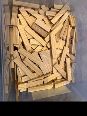 Byggklossar i trä från Micki - En låda med rektangulära byggklossar i ljust trä från Micki. Perfekt för att bygga kreativa konstruktioner och stapla höga torn. Klossarna är släta och har en naturlig träfärg med tydliga ådringar.