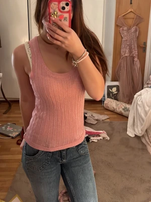 Rosa ribbad linnetopp från Zara - Säljer en ljusrosa ribbad linnetopp från Zara. Toppen är ärmlös med rund halsringning och har en glittrig finish som ger extra detalj. Perfekt att styla med jeans eller kjol för en trendig look.