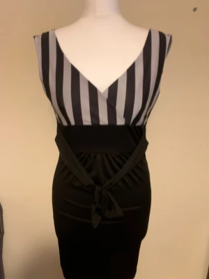 Dress - Säljer två snygga klänningar! En svartvit randig omlottklänning med knyt i midjan och en marinblå blommig klänning med korta ärmar och öppen axel. Perfekta för dig som vill ha något unikt och stilrent i garderoben.