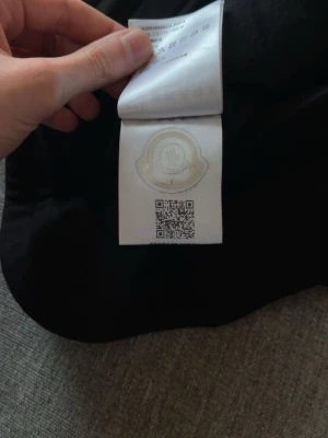 Svarta mjukisbyxor från Moncler - Säljer ett par svarta mjukisbyxor från Moncler med ett unikt geometriskt mönster över hela byxan. Byxorna har resår i midjan och är tillverkade i ett mjukt material som känns riktigt skönt. Perfekta för en chill och stilren look.