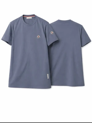 Blå Moncler t-shirt i bomull - Snygg blå t-shirt från Moncler med rund hals och diskret Moncler-logga på bröstet och ärmen. Tillverkad i mjuk bomull och har en klassisk passform som passar perfekt till jeans eller shorts.