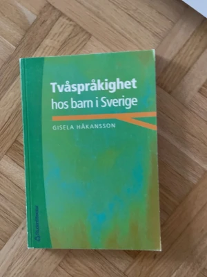 Tvåspråkighet hos barn i Sverige - Kursbok om tvåspråkighet hos barn i Sverige, skriven av Gisela Håkansson. Boken har ett grönt och orange mjukt omslag och är tryckt av Studentlitteratur. Perfekt för dig som pluggar språkvetenskap eller pedagogik.