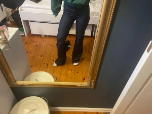 Mörkblå bootcut jeans - Säljer ett par mörkblå bootcut jeans med hög midja och klassisk femficksdesign. Jeansen har en snygg utsvängd passform nedtill och är tillverkade i ett stretchigt denimtyg som sitter bekvämt. Perfekta för en trendig och avslappnad look.