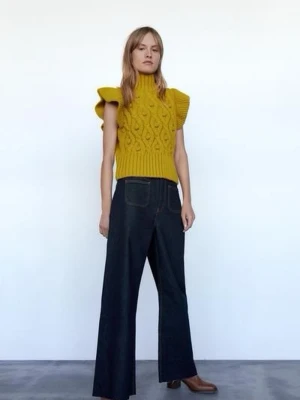 STICKAD VÄST MED TOFSAR - Säljer en stickad väst med tofsar. Toppen har en hög hals och ribbad nederkant som ger en schysst passform.