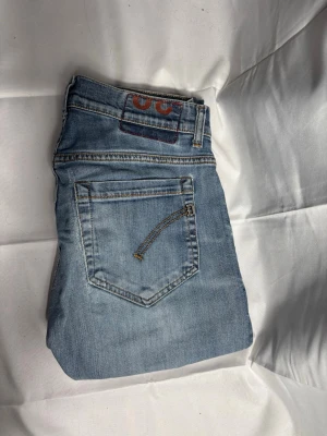 Dondup geroge - Snygga ljusblå jeans från George med klassisk femficksdesign och kontrastsömmar. Jeansen har en rak passform och är tillverkade i bomullsdenim. Perfekta för en avslappnad och trendig look.