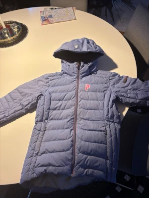 Ljusblå dunjacka från Peak Performance - Peak performance dunjacka, använts som skidjacka. I bra skicka, men finns en liten lagning längst ner på baksidan. Pris kan diskuteras 