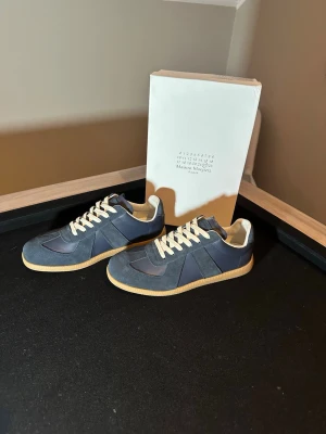 Blåa Maison Margiela  - Riktigt fräscha Maison Margielas                                    Skick:10/10 aldrig använda säljer på grund av att det är för små.                                                                   Färg: Blå.                                                                                Storlek:43 men är rätt så små i storleken så passar även storlek 42.                                                     Hör av er vid funderingar eller prisförslag 