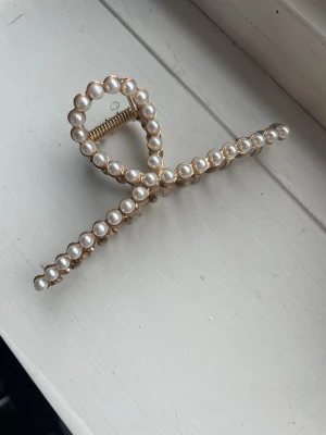 Hårklämma i guld med pärlor. - Säljer en fin hårklämma i guld från glitter. Använd fåtal gånger men inget som syns. Tappat lite färg men inget som syns när man har den på sig. Kontakta om du är intresserad