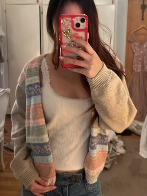 Pastellmönstrad kofta med knappar - Superfin kofta med pastellfärgade ränder i beige, blått, grönt, rosa och orange. Koftan har v-ringning, ribbade muddar och knäppning framtill. Perfekt för lager-på-lager och ger en mysig vintagekänsla.