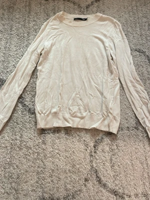 Vit tröja från lager157 - En enkel och stilren vit tröja från lager 157  med rund halsringning och långa ärmar. Tröjan har ribbade muddar vid ärmslut och nederkant. Perfekt att matcha med jeans eller kjol för en avslappnad look.