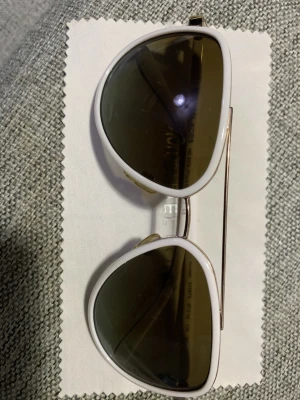 Vita pilotbågar från Michael Kors äkta.  - Snygga solglasögon från Michael Kors med klassisk pilotform. Bågarna är vita med gulddetaljer och mörka linser. Perfekta för att lyfta din stil under soliga dagar. Sparsamt användning och äkta. Priset kan diskuteras.