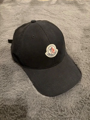 Moncler Keps - Nu säljes en otroligt fin Moncler Keps som ej använts. Otroligt fint skick och passar bra, går att justera bak. Har du frågor eller funderingar? Hör av dig!