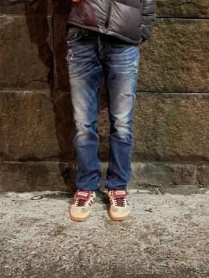 Blå jeans med slitningar - Blå jeans med egengjorda slitningar i mycket fint skick. Märket är diesel men som sagt egengjord design. Storleken är 30/32 och dessa jeans passar perfekt när som helst! 🤩