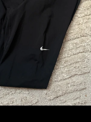 Svarta leggings från Nike Pro  - Svarta leggings från Nike med klassisk vit swoosh-logga på benet. De är stretchiga och har en tight passform, perfekta för träning eller chill. Materialet är mjukt och följsamt, vilket gör dem riktigt bekväma att ha på sig.