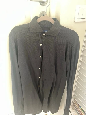  Slim fit skjorta från Eton - Knappt använd skjorta från Eton i slim fit-modell med diskret randigt mönster. Skjortan har klassisk krage, vita knappar och lång ärm. Perfekt för dig som gillar stilrena plagg med en twist. 