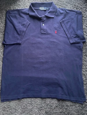 Polo Ralph Lauren Pikétröja XL | Fint Skick! XL - Klassisk marinblå Polo Ralph Lauren piké i strl XL. Fint skick! Perfekt basplagg till våren och sommarens alla fester och grillkvällar m.m! ✨🧵 Märke & Modell: Polo Ralph Lauren – Klassisk Mesh Piké. 📏 Storlek & Passform: XL, klassisk passform. 🧩 Material: Premium 100% Bomull. 📐 Mått: Längd 72 cm. Bredd (Armhåla till armhåla) 59,5 cm. ✅ Skick: 8/10 - Fint skick. 💰 Nypris: Ca 1300 kr. ‼️ Skickas inom 24h ‼️ 