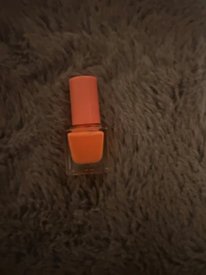 Orange nagellack i fyrkantig flaska - Snyggt orange nagellack i en stilren fyrkantig glasflaska med matchande orange lock. Perfekt för dig som vill ha en färgstark look på naglarna. Lacket har en krämig finish och är lätt att applicera.