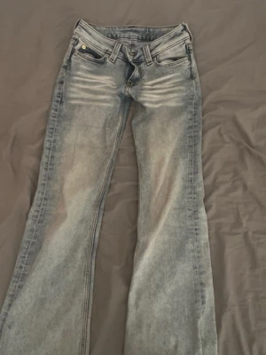 Ljusblå lågmidjade bootcut jeans med slitningar - Fina lågmidjade jeans! Med en grön lapp! Använd fåtal gånger. Har vita streck längst upp på benen!(Det är meningen) vid frågor skriv gärna!🙏🏼 Säljer pågrund av att de inte kommer till användning!stolek : 25/30