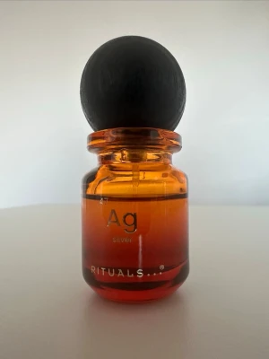 Rituals parfymflaskor Ag & Au - Två exklusiva parfymflaskor från Rituals, Ag Silver och Au Gold. Flaskorna är gjorda av glas med en gradient från orange till röd och har en stor, rund svart kork. Perfekt för dig som vill ha en unik och snygg detalj på parfymhyllan. 12ml+ kvar i båda