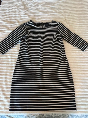 Randig svartvit klänning  - Snygg svartvit randig klänning från Only med trekvartsärm och rund halsringning. Klänningen har dragkedja i nacken och är i mjukt bomullsmaterial. Perfekt för dig som gillar enkel och stilren design.