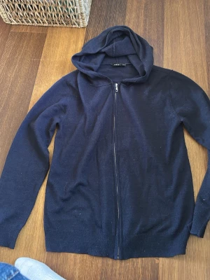 Svart hoodie med dragkedja - En enkel svart hoodie från rylvs of Stockholm med dragkedja framtill och huva. Tillverkad i mjukt material och har långa ärmar samt ribbade muddar vid ärmslut och nederkant. Perfekt för en avslappnad stil.