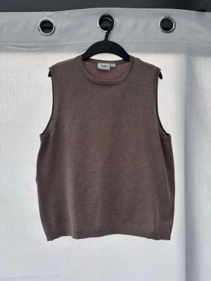 Brun stickad väst från Saint Tropez - Säljer en brun stickad väst från Saint Tropez i storlek XS. Västen har en klassisk rund halsringning och ribbade kanter vid ärmhål och nederkant. Perfekt att styla över en skjorta eller t-shirt för en trendig lager-på-lager-look. Inga defekter