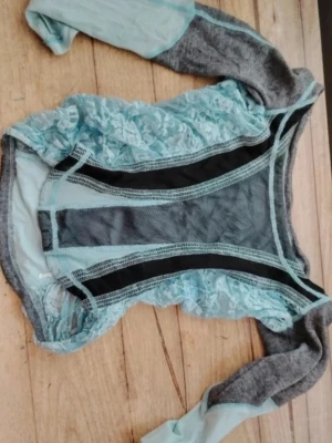 Vintage Blågrå tröja med meshdetaljer💎  - Unik tröja i ljusblått och grått med långa ärmar🤩 Tröjan har detaljer i spets och mesh samt svarta inslag framtill. Materialmixen av spets, mesh och tyg ger en cool och modern känsla❤️ Perfekt för dig som gillar att sticka ut med din stil☀️ 