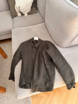 Svart linnéjacka med dragkedja - Snygg grön jacka i linne med klassisk krage och hel dragkedja framtill. Jackan har en minimalistisk design och raka ärmar, perfekt för dig som gillar stilrena plagg. Passar till både vardagslooken och när du vill klä upp dig lite extra.