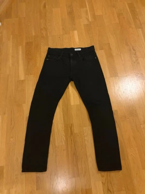 Svarta jeans från Tiger of Sweden - Snygga svarta jeans från Tiger of Sweden med klassisk femficksmodell och raka ben. Jeansen har en stilren look och är tillverkade i ett mjukt och stretchigt material som sitter skönt. Perfekta för dig som gillar en enkel men trendig stil.