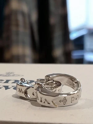Vivienne Westwood silver hoops - Säljer ett par chunky silvriga hoops från Vivienne Westwood. Örhängena har ingraverad text och små ikoniska orb-detaljer runt hela ringen. 