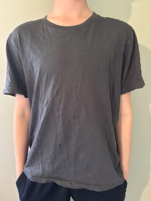 Mörkgrå basic t-shirt  - Enkel och stilren mörkgrå t-shirt med rund hals och korta ärmar. Tillverkad i mjuk bomull och har en avslappnad passform som passar perfekt till vardagslooken.