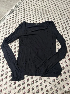 Svart långärmad topp från BikBok - En svart långärmad topp från BikBok i mjuk bomull. Toppen har en enkel och stilren design med rund halsringning och smal passform. Perfekt att matcha med jeans eller kjol för en clean look.