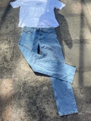 Ljusblå jeans från Jack & Jones - Säljer ett par klassiska ljusblå jeans från Jack & Jones med rak passform och fem fickor. Jeansen har en snygg vintagekänsla och är tillverkade i 100% bomull. Perfekta för en avslappnad och trendig stil.